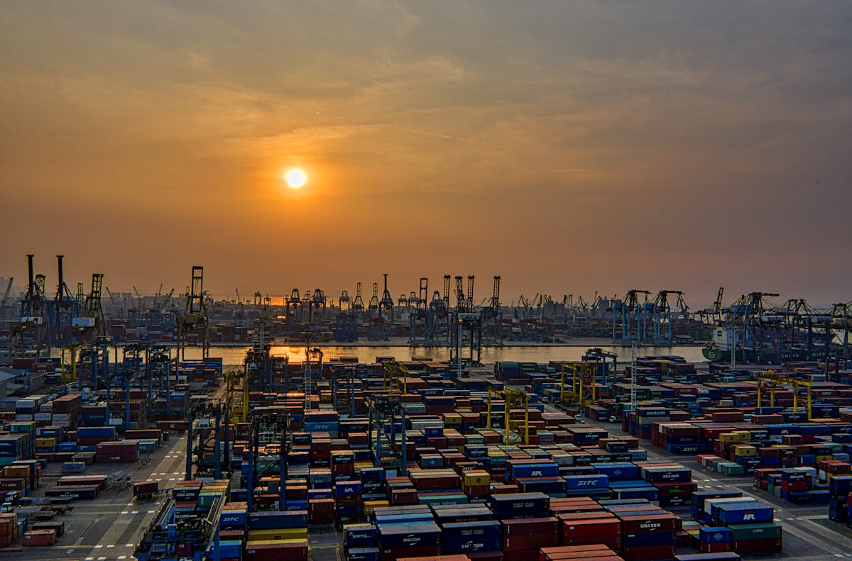Container port at sunset with shipping containers and cranes — drayage operations